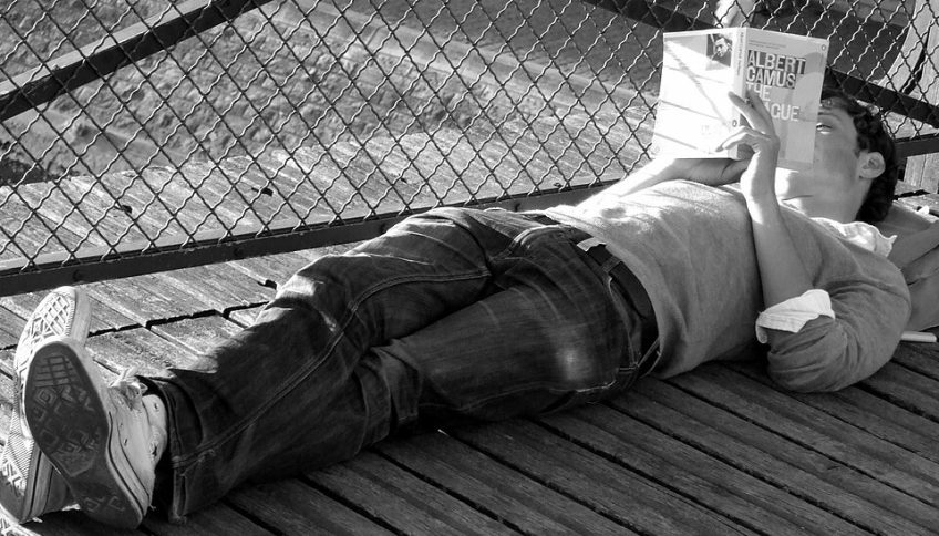 Un hombre lee una edición en inglés de La peste en el Pont des Arts de París